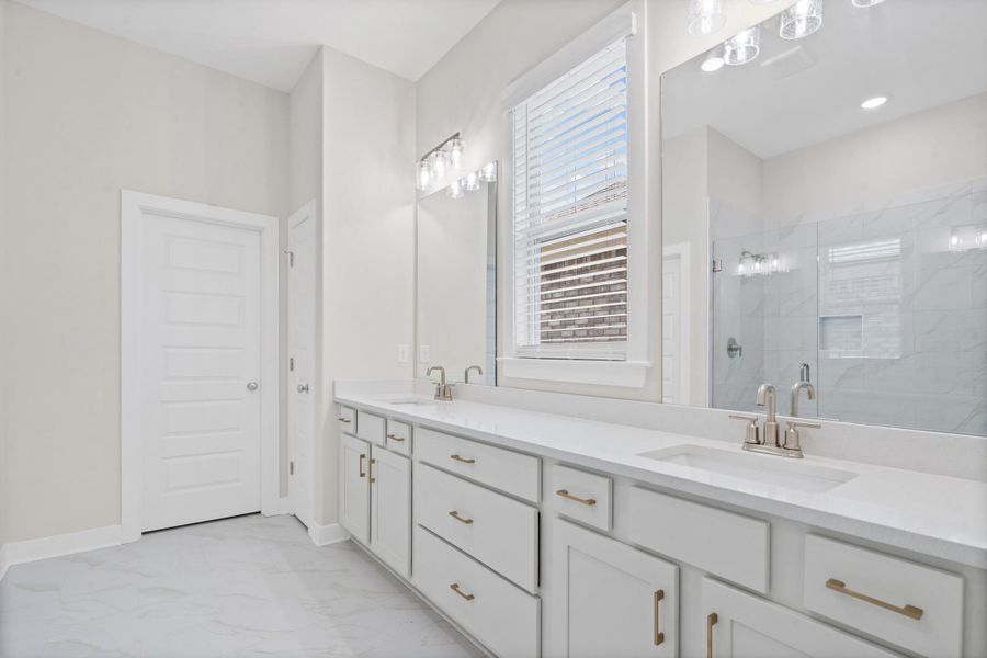 Dual vanity with white cabinetry, gold-tone hardware, and light countertops