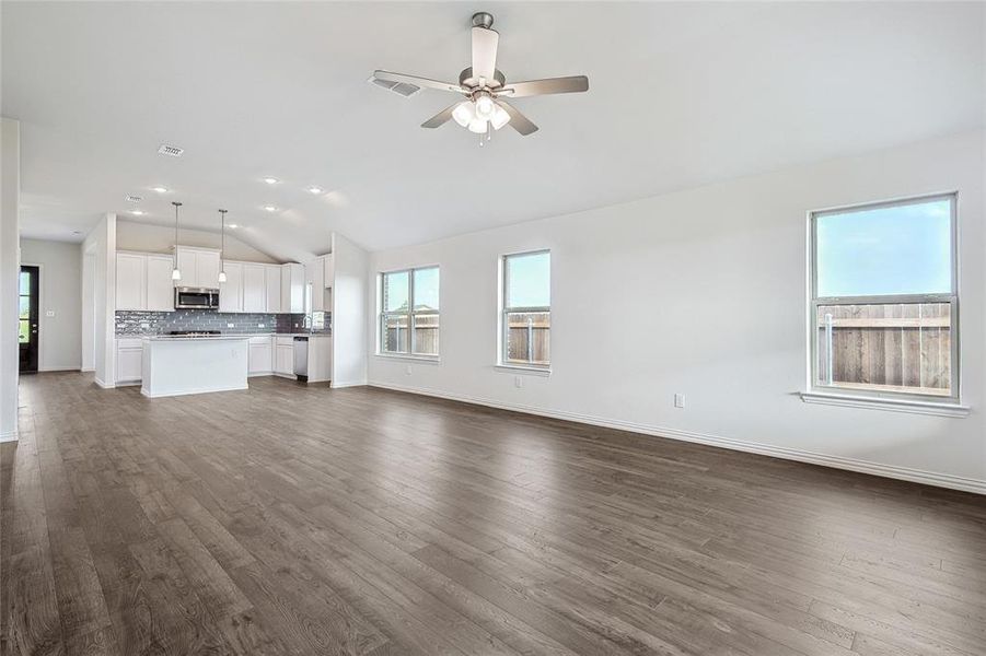 Unfurnished living room with ceiling fan, lofted ceiling, and dark hardwood / wood-style flooring