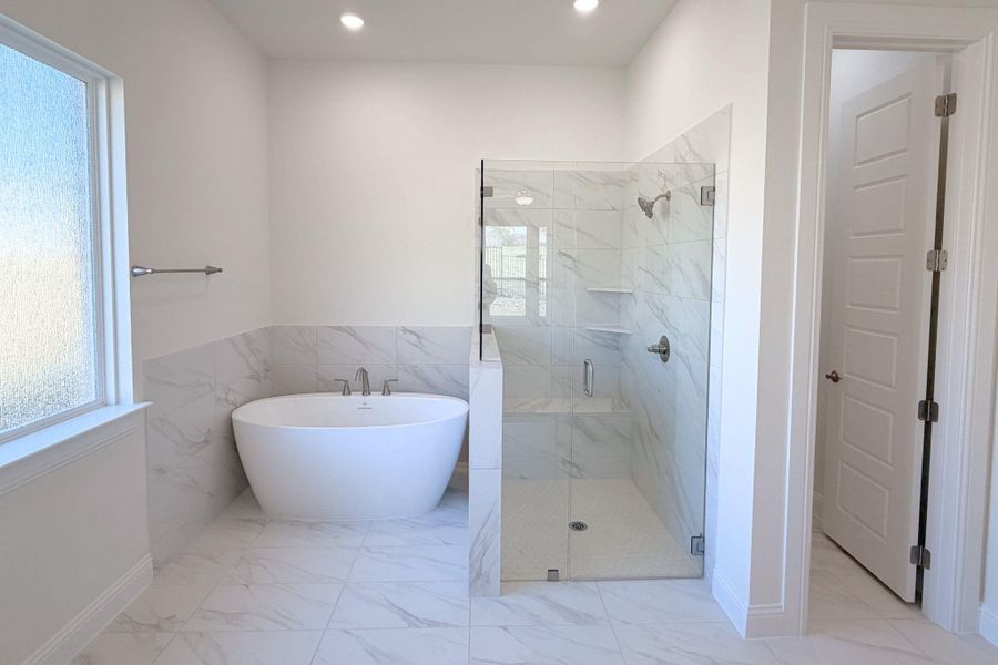 Full bathroom featuring a marble finish shower, a freestanding bath, light marble finish floors, healthy amount of natural light, and recessed lighting