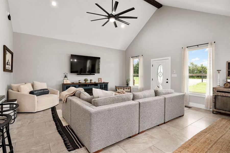 Enter to a large living room with vaulted ceiling and wood beam.