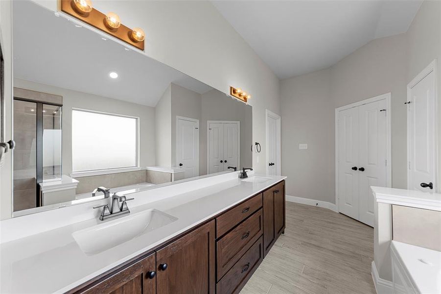 Bathroom with double vanity, a garden tub, a stall shower, light wood-style floors, and recessed lighting