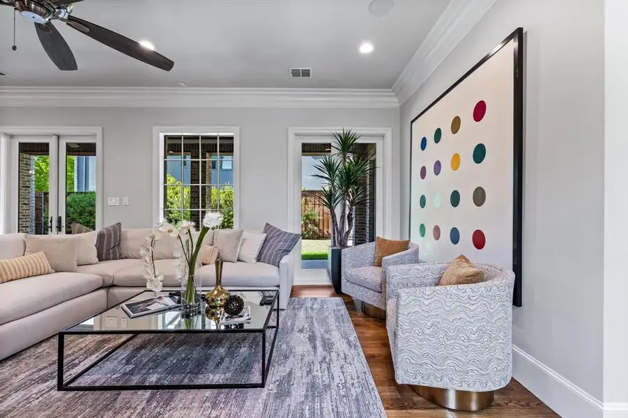 Living room featuring ceiling fan, crown molding, and dark wood-type flooring