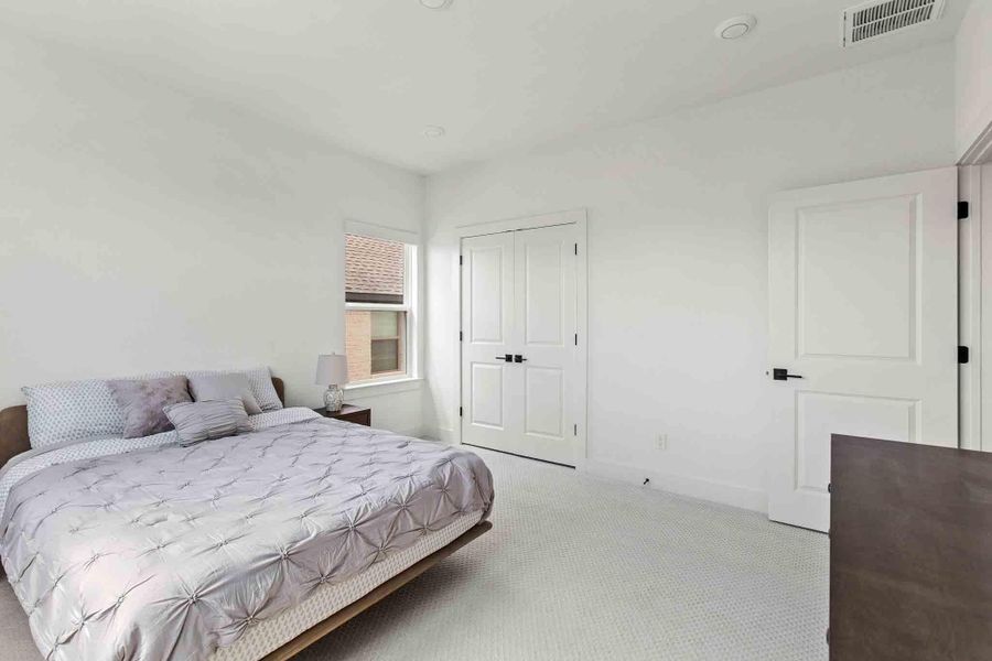 Spacious room featuring light-colored carpeting, white walls, and a window with a view of brick siding
