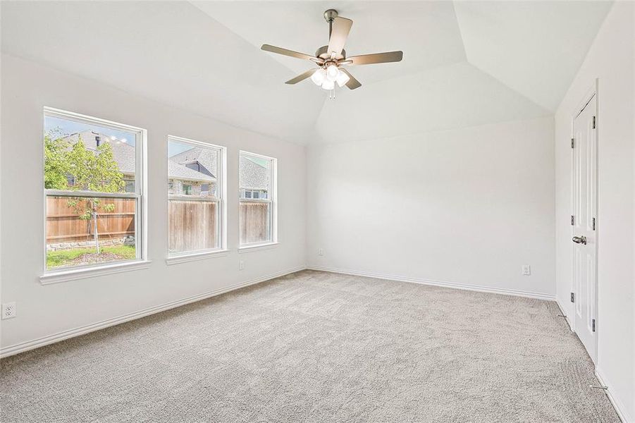 Carpeted empty room with ceiling fan and vaulted ceiling