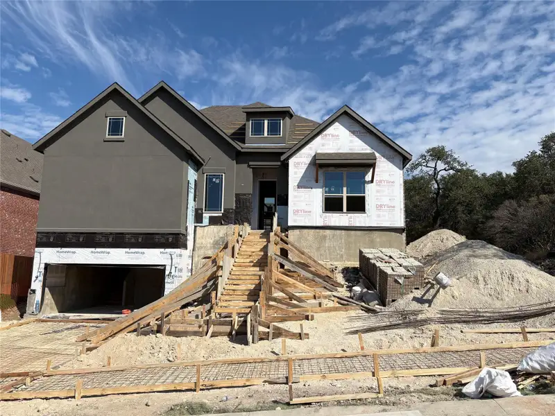 Property under construction with an attached garage, stucco siding, driveway, and a shingled roof
