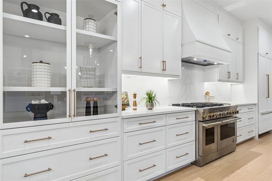 Custom cabinetry with glass-front display, abundant storage, and a professional-grade range, blending function with timeless design.