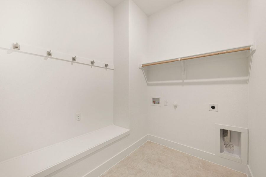 Laundry room with wall hooks, built-in bench, hanging rod, shelf, and washer-dryer hookups on tile floor