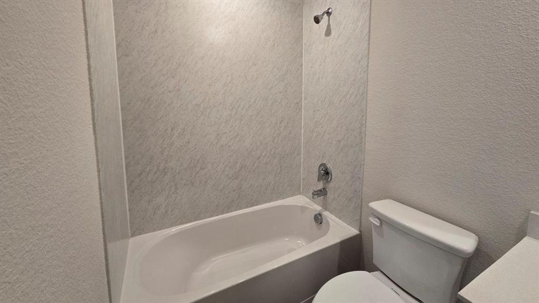 Bathroom with a textured wall, vanity, and bathing tub / shower combination