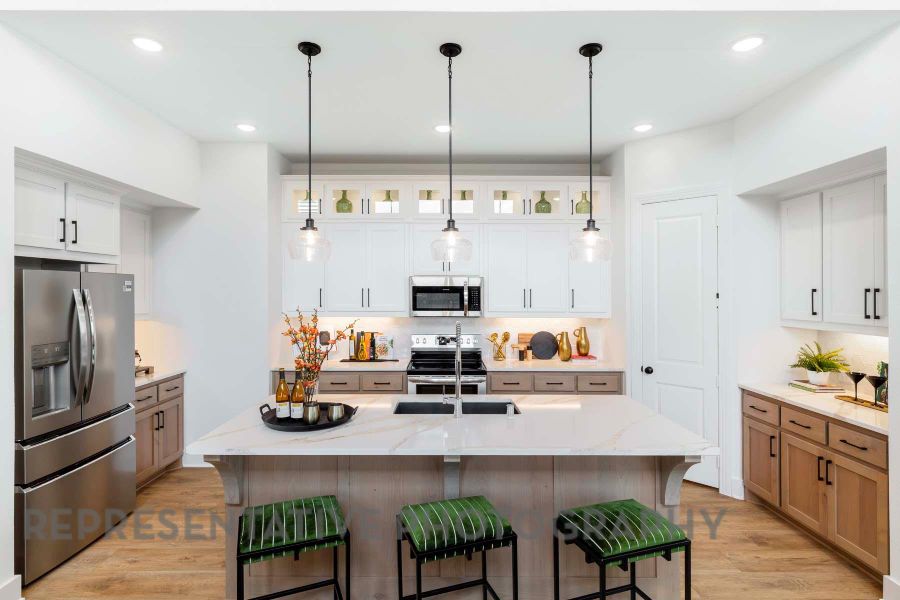 Kitchen with light wood-type flooring, a kitchen bar, stainless steel appliances, and pendant lighting Kitchen with light wood-type flooring, a kitchen bar, stainless steel appliances, and pendant lighting