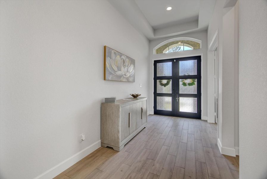 The beautiful foyer showcases 12' tray ceilings and recessed lighting, all framed by an impressive double-door entry that sets a refined tone the moment you step inside.