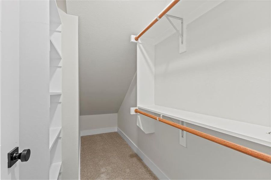 Walk in closet with light carpet and lofted ceiling