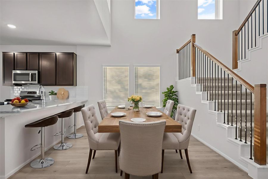 This virtually staged kitchen and dining area showcases a warm and welcoming heart of the home. The space features a spacious breakfast bar, gleaming granite countertops, stylish cabinetry, and plenty of natural light, offering a perfect setting for gatherings or family meals. The Dramatic two-story wall of windows makes this floor plan timeless! This virtually staged kitchen and dining area showcases a warm and welcoming heart of the home. The space features a spacious breakfast bar, gleaming granite countertops, stylish cabinetry, and plenty of natural light, offering a perfect setting for gatherings or family meals. The Dramatic two-story wall of windows makes this floor plan timeless!