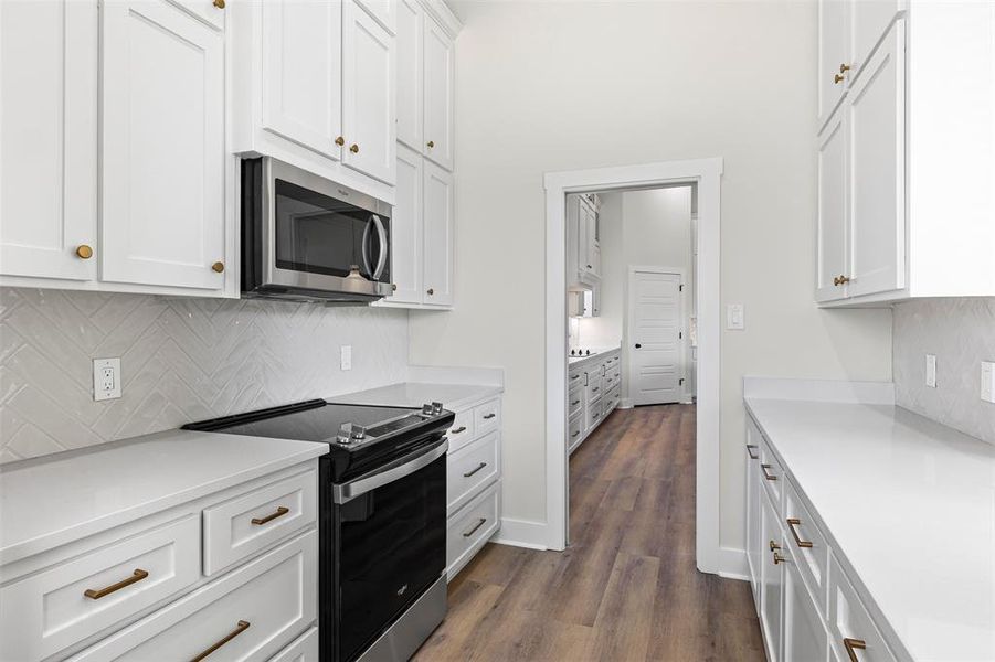 Kitchen featuring tasteful backsplash, range with electric cooktop, and white cabinets Kitchen featuring tasteful backsplash, range with electric cooktop, and white cabinets