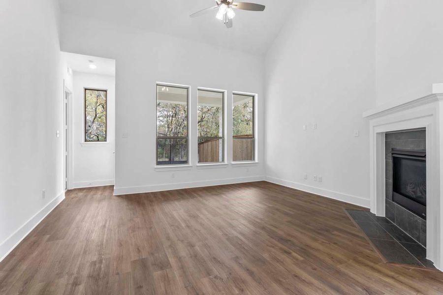 Unfurnished living room featuring a tile fireplace, dark wood finished floors, high vaulted ceiling, and ceiling fan Unfurnished living room featuring a tile fireplace, dark wood finished floors, high vaulted ceiling, and ceiling fan
