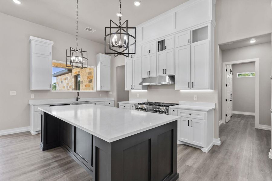 A well-appointed kitchen features a large central island, crisp white cabinetry, and modern pendant lighting. A well-appointed kitchen features a large central island, crisp white cabinetry, and modern pendant lighting.
