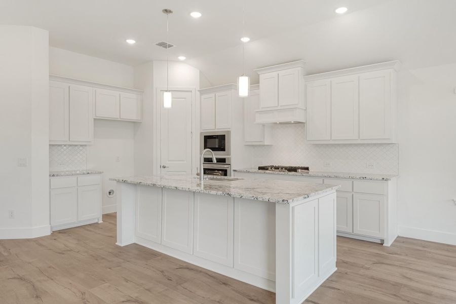 Kitchen with white cabinets, granite island, stainless steel appliances, and light wood floors Kitchen with white cabinets, granite island, stainless steel appliances, and light wood floors