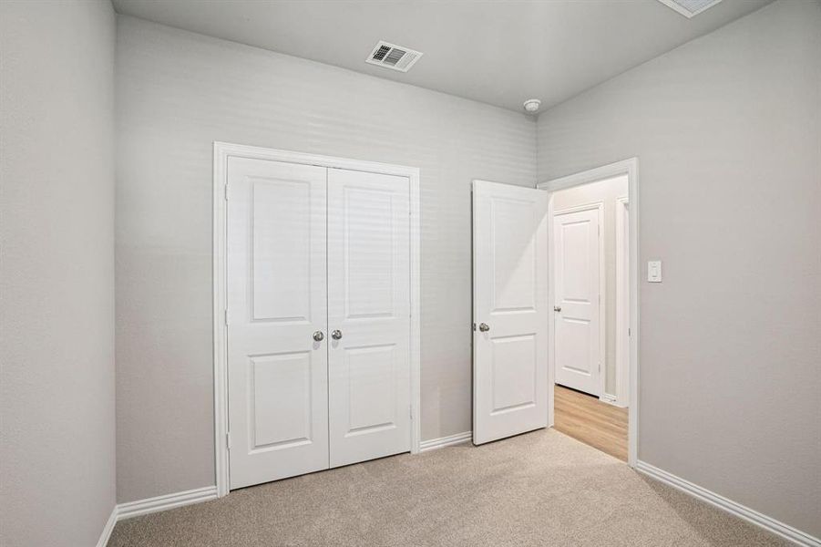 Unfurnished bedroom with light carpet and a closet