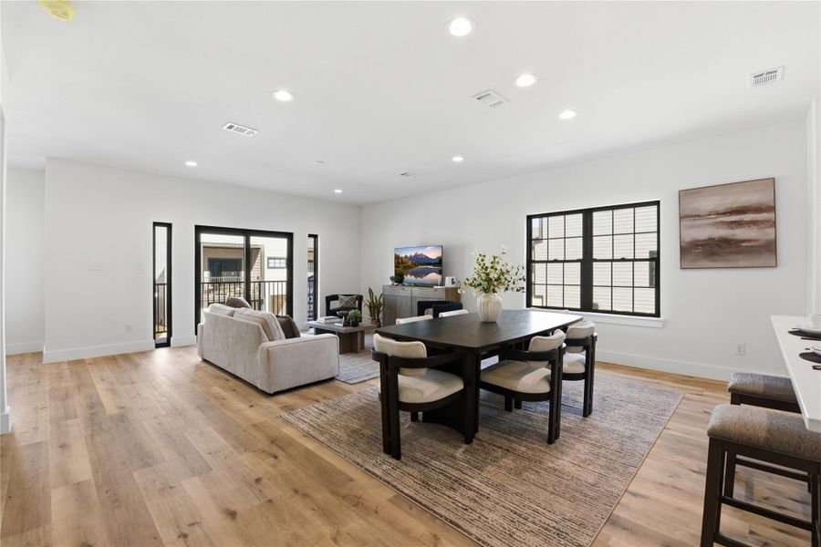 The room is brightened by ample natural light from large windows and a sliding glass door leading to a balcony.