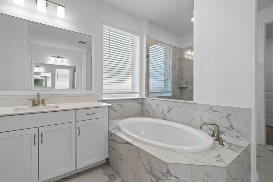 The centerpiece of this contemporary primary bath is the deep, freestanding bathtub, offering an ideal spot for relaxation with a unique view into the walk-in shower.