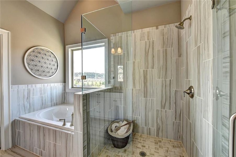 Bathroom with tile flooring, shower with separate bathtub, and vaulted ceiling