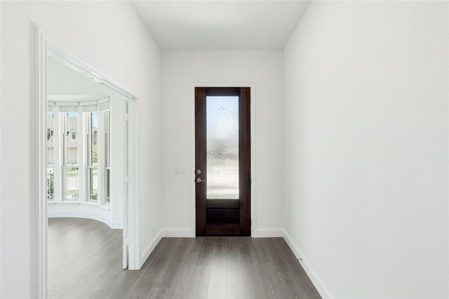 Entryway with dark wood front door, frosted glass panel, gray hardwood floors, and white walls Entryway with dark wood front door, frosted glass panel, gray hardwood floors, and white walls