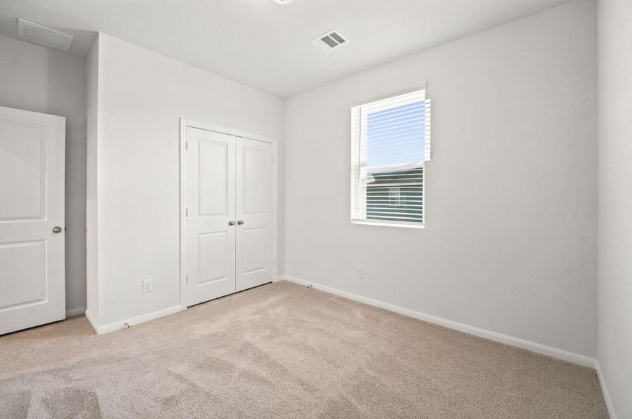 Soft carpeting pairs with neat trim and a double-door closet in this quiet bedroom.