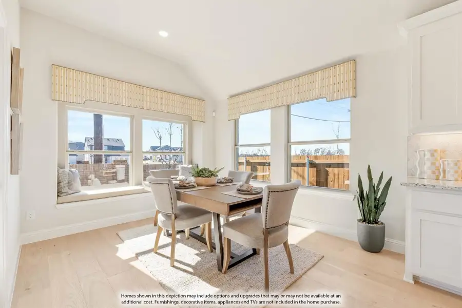 Bright dining area with wood table, four chairs, window seat, and hardwood floors surrounded by large windows