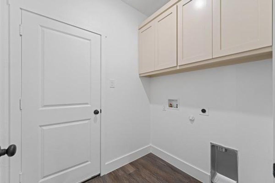 Dedicated laundry area featuring wood-finish flooring, white walls, and built-in upper cabinetry Dedicated laundry area featuring wood-finish flooring, white walls, and built-in upper cabinetry
