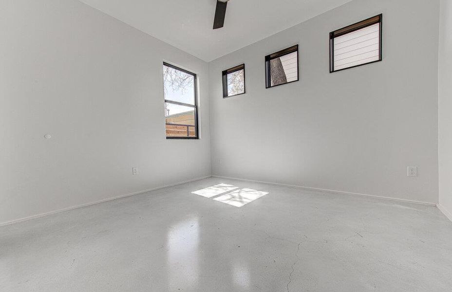 Spare room featuring ceiling fan, concrete floors, and baseboards