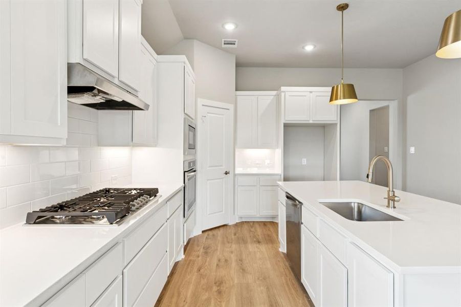 Kitchen with light wood-style floors, backsplash, white cabinetry, hanging light fixtures, and recessed lighting