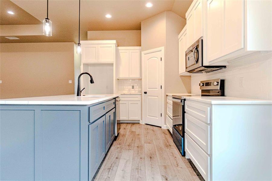 Kitchen featuring white cabinetry, appliances with stainless steel finishes, sink, and pendant lighting