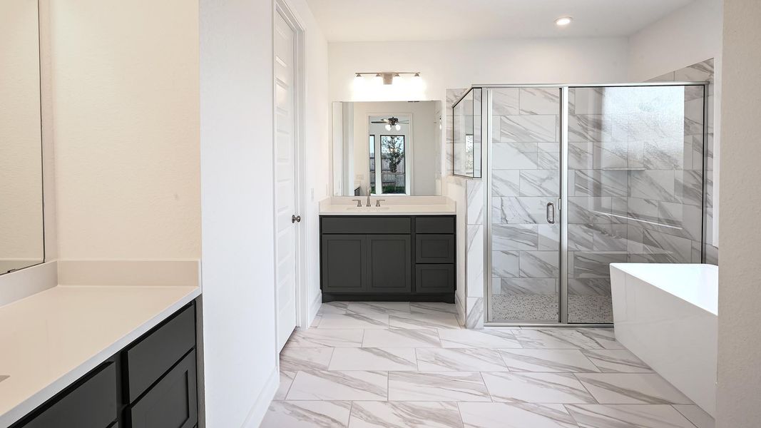Bathroom with light marble finish flooring, a shower stall, a soaking tub, and vanity Bathroom with light marble finish flooring, a shower stall, a soaking tub, and vanity