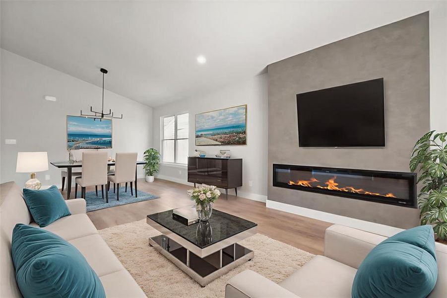 Living area featuring wood finished floors, a glass covered fireplace, lofted ceiling, and recessed lighting Living area featuring wood finished floors, a glass covered fireplace, lofted ceiling, and recessed lighting