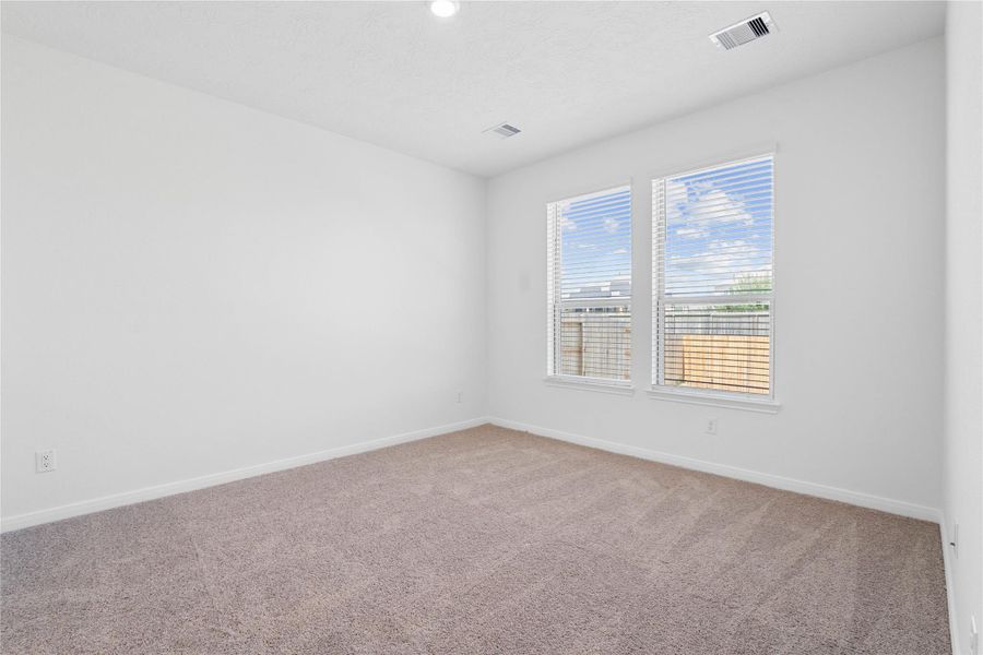 Unwind after a long day in this stunning primary suite! This spacious retreat features plush carpeting, neutral-toned walls, high ceilings, recessed lighting, and large windows with privacy blinds for comfort and tranquility.