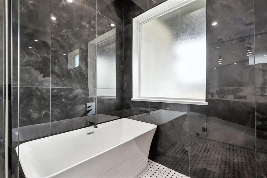 Bathroom with tile walls, a soaking tub, and a stall shower