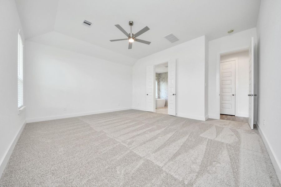 Escape and relax in the exquisite primary suite, a haven to unwind after a long day. The spacious room, located on first floor, boasts plush carpeting, soothing paint tones, high ceilings, and expansive windows adorned with privacy blinds.