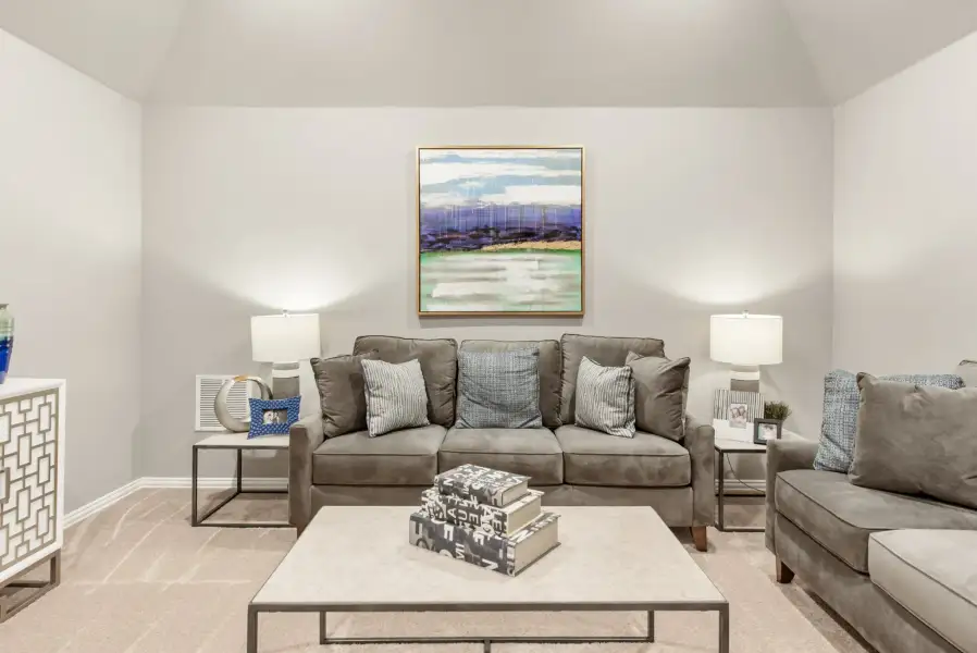Living room with gray sofa, vaulted ceiling, and abstract wall art above a square coffee table