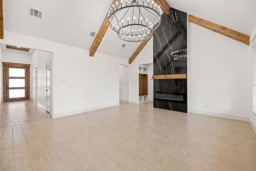 Unfurnished living room featuring visible vents, a chandelier, beamed ceiling, and wood finished floors