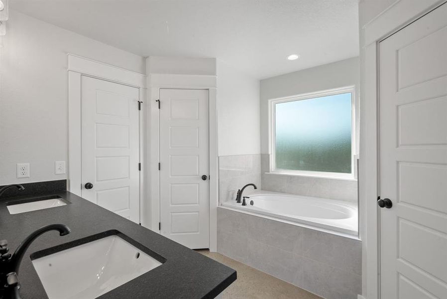 Bathroom featuring vanity and tiled bath