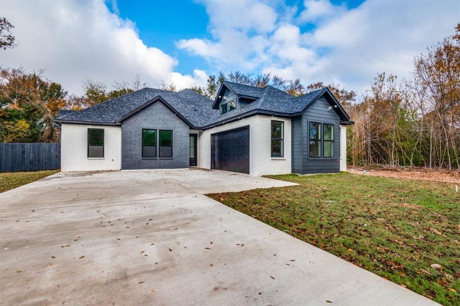 View of front of home with a garage and a front lawn