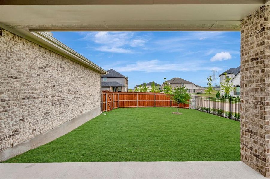 Covered concrete patio overlooking a manicured lawn