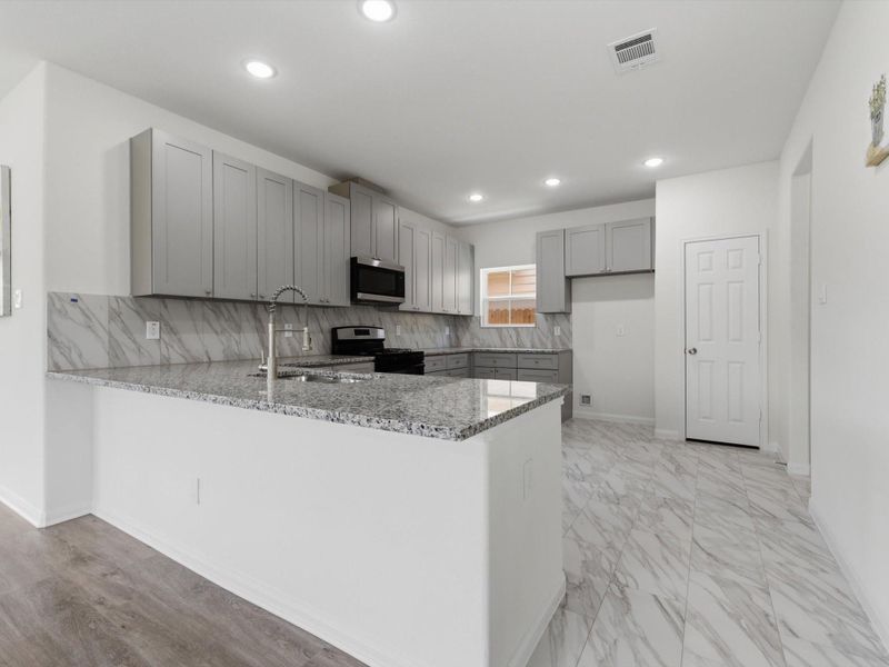 At the center of the home, the kitchen blends style and practicality with granite surfaces, stainless appliances, soft-close cabinetry, and abundant storage. At the center of the home, the kitchen blends style and practicality with granite surfaces, stainless appliances, soft-close cabinetry, and abundant storage.