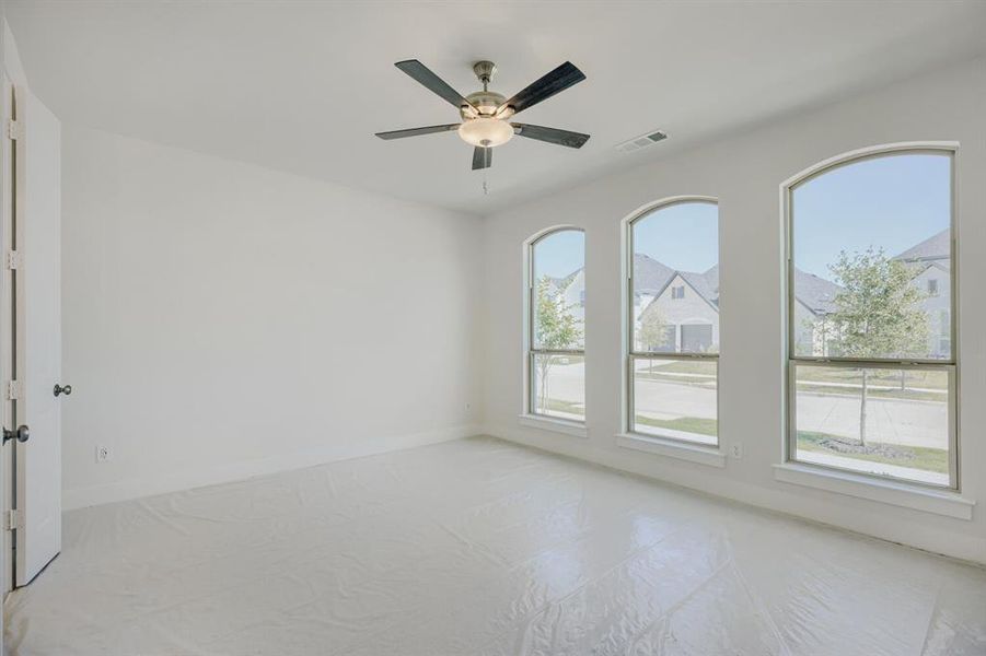 Spacious room featuring three arched windows, a ceiling fan with integrated lighting, and a white interior door with dark hardware