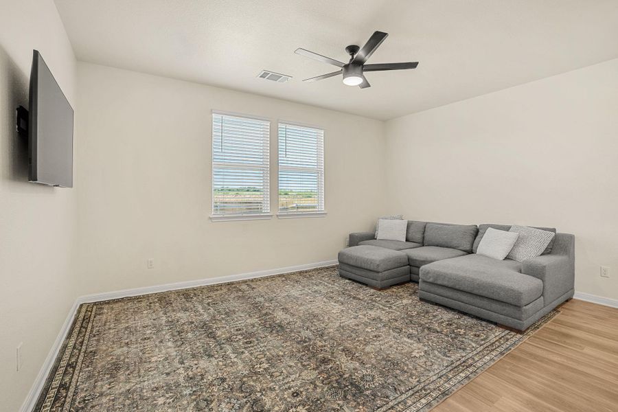 Well-lit living area features a modern ceiling fan and durable flooring, creating an inviting atmosphere.