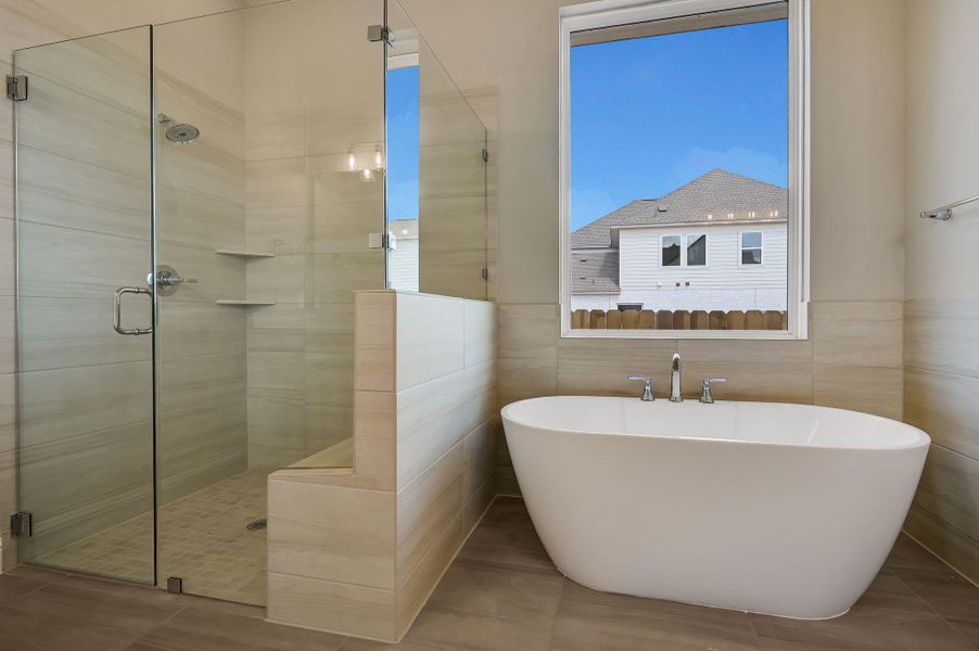 Bathroom with a stall shower, a freestanding bath, and tile walls