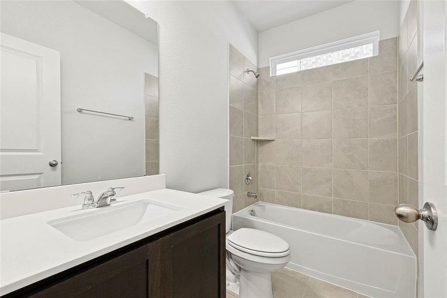 Full bathroom featuring vanity, tiled shower / bath, tile patterned floors, and toilet