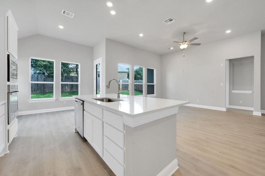 Kitchen featuring light wood-type flooring, a kitchen island with sink, a ceiling fan, light countertops, and recessed lighting