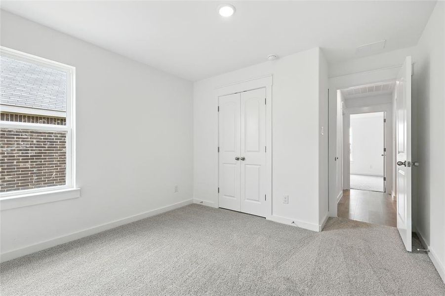 Unfurnished bedroom featuring light carpet, a closet, and recessed lighting