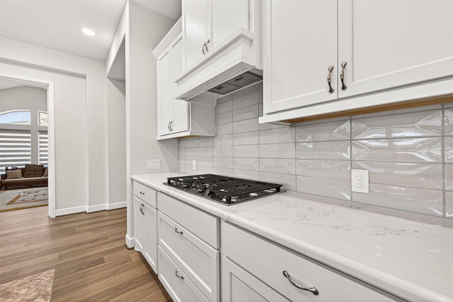 Chef’s kitchen complete with quartz countertops, gas cooktop, smart vent hood, and beautiful upgraded subway tile backsplash Chef’s kitchen complete with quartz countertops, gas cooktop, smart vent hood, and beautiful upgraded subway tile backsplash