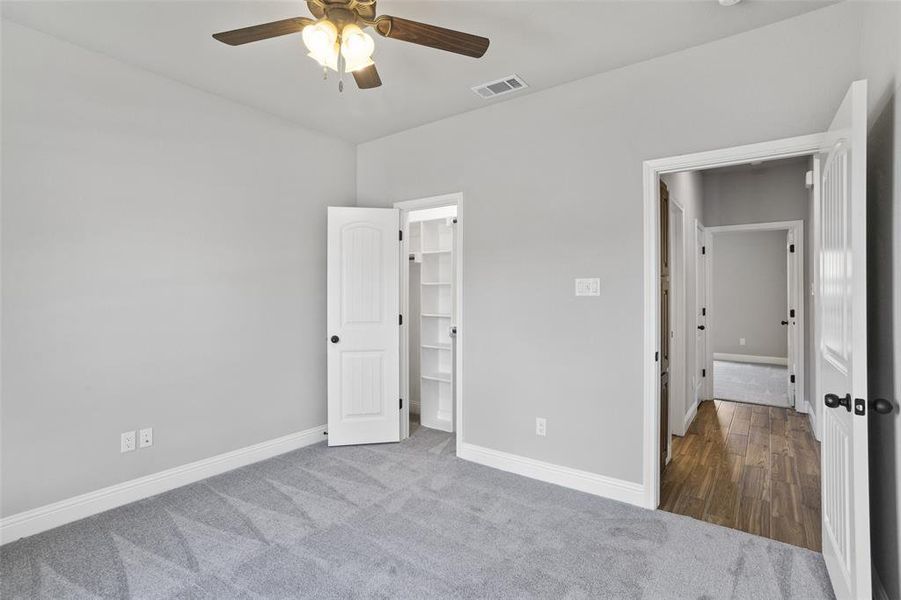 Unfurnished bedroom with carpet floors, a spacious closet, ceiling fan, and a closet